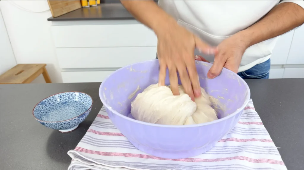 amasando masa elástica para focaccia italiana en bol morado