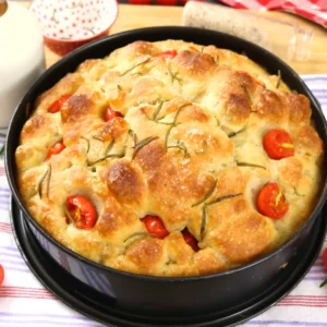 Focaccia sin amasar alta y esponjosa con tomates cherry y romero, horneada en molde redondo