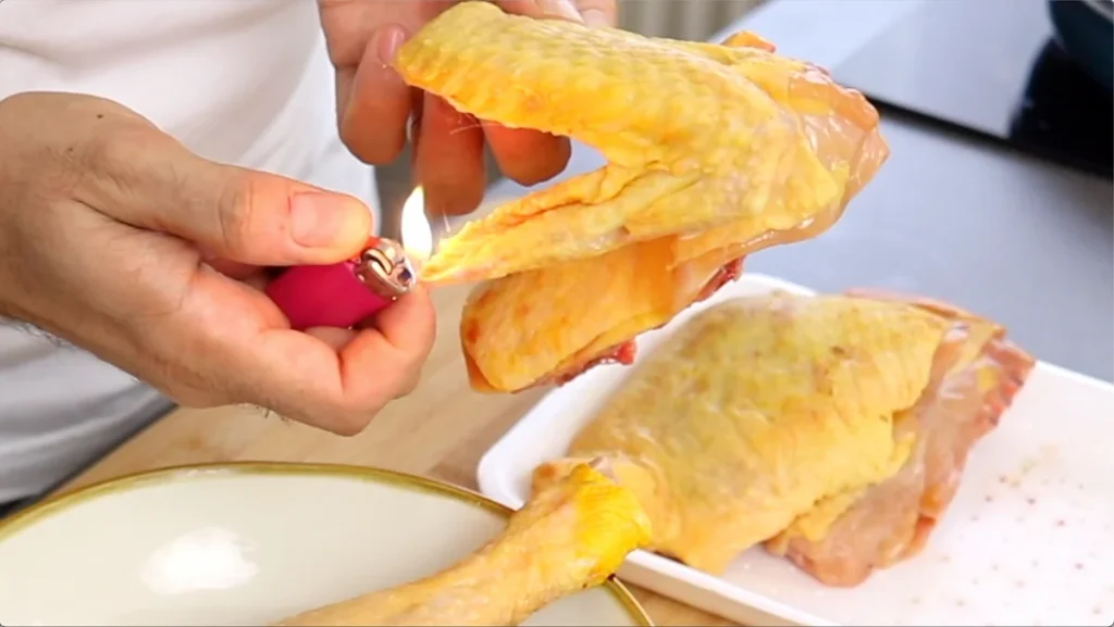 Quemamos los pequeños restos de plumas del pollo pasando rápidamente una llama por la superficie