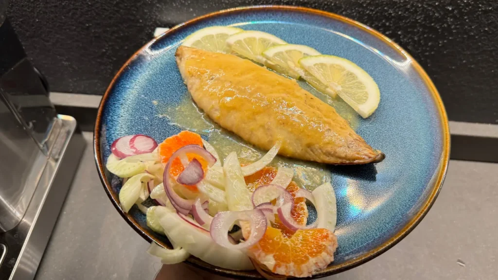caballa al limón en sartén servida con ensalada de hinojo, naranja y cebolla roja