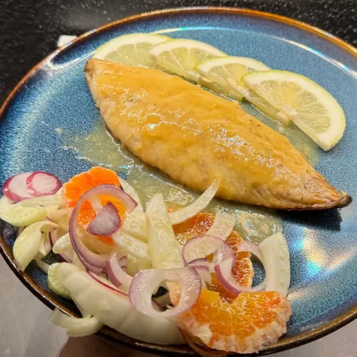 caballa al limón en sartén servida con ensalada de hinojo, naranja y cebolla roja