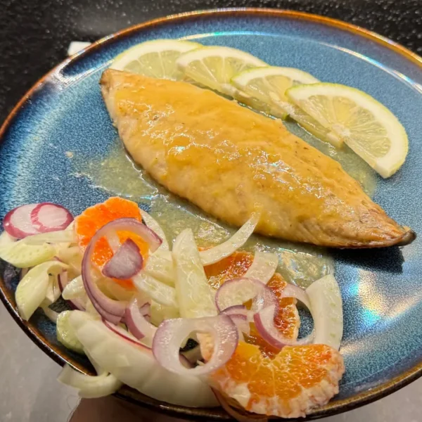 caballa al limón en sartén servida con ensalada de hinojo, naranja y cebolla roja