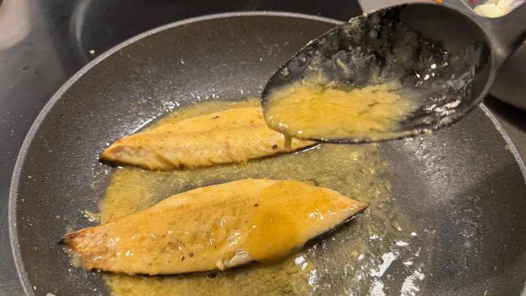 filetes de caballa dorándose en sartén con salsa de limón