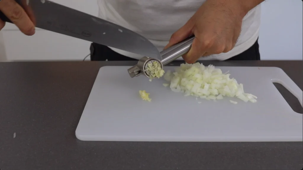 Cortar la cebolla en cubitos brunoise y prensar el ajo