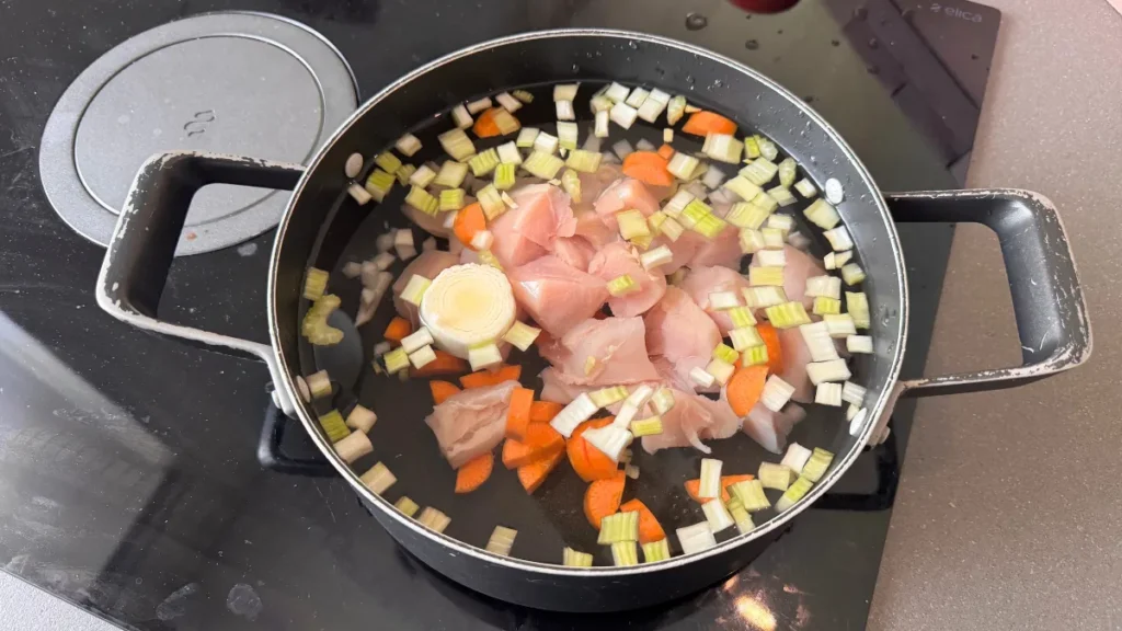 Poner verduras y pollo dentro de la olla con agua