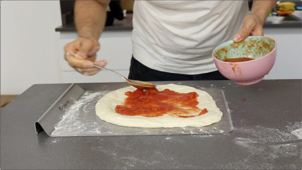 Extendemos una capa fina de tomate sobre la pizza